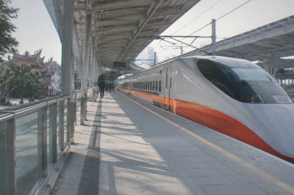A high speed rail train standing at a platform in a modern station in daylight