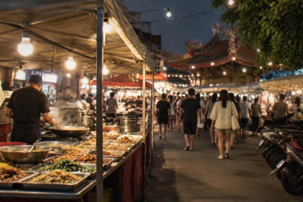 A busy Tainan night market stall at night with vendors cooking behind a counter of displayed dishes