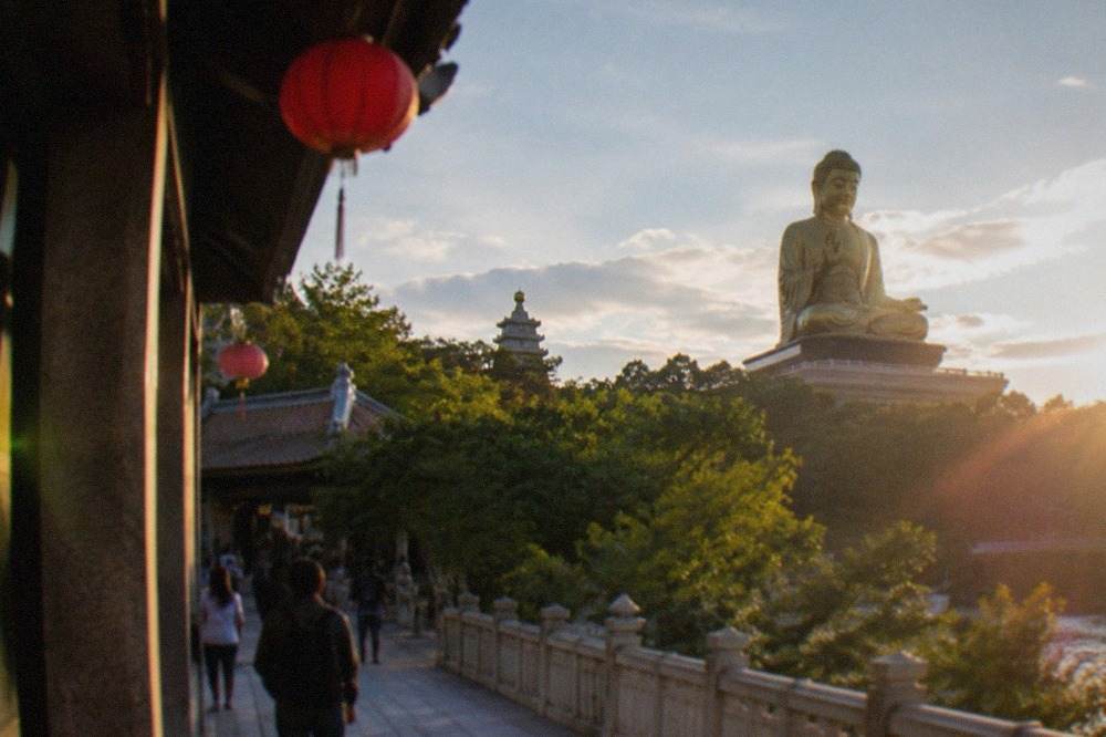 A large golden seated Buddha statue rising above trees at a monastery in southern Taiwan