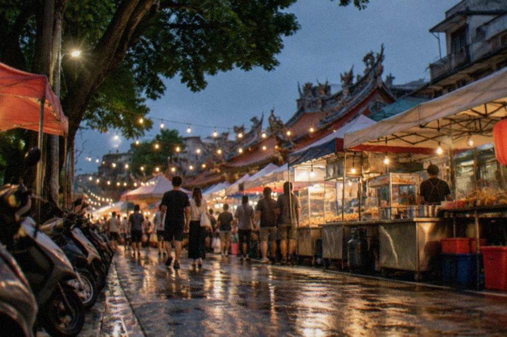 A night market lane lit by strings of bulbs with food stalls on both sides
