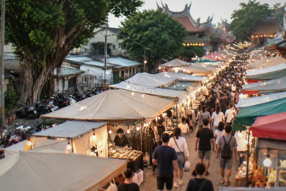 A busy Tainan night market aisle lit by stall lights in the evening