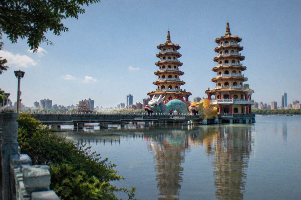 An ornamental lake with a dragon-shaped pagoda tunnel and temple rooftops reflected in still water