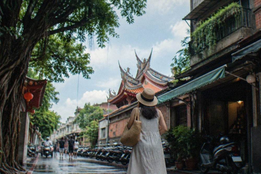 A visitor in a traditional qipao dress walking along an old brick lane in Anping