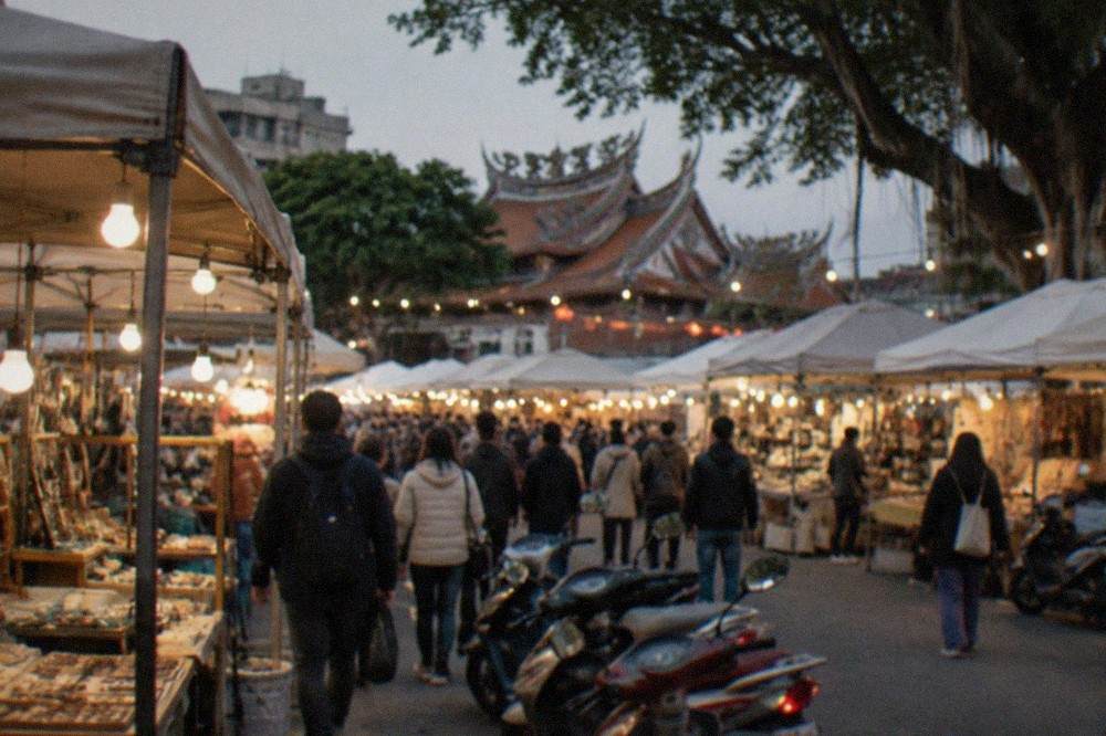 Crowded night market stalls with glowing food signs in Tainan after dark