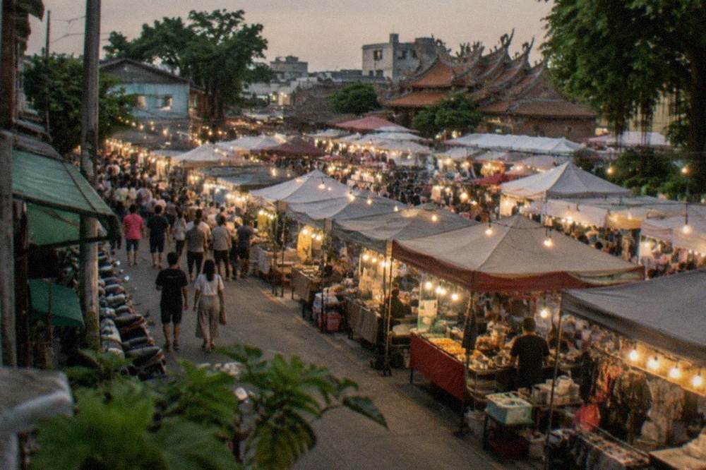 Crowded night market aisles in Tainan with food stall lights and visitors browsing