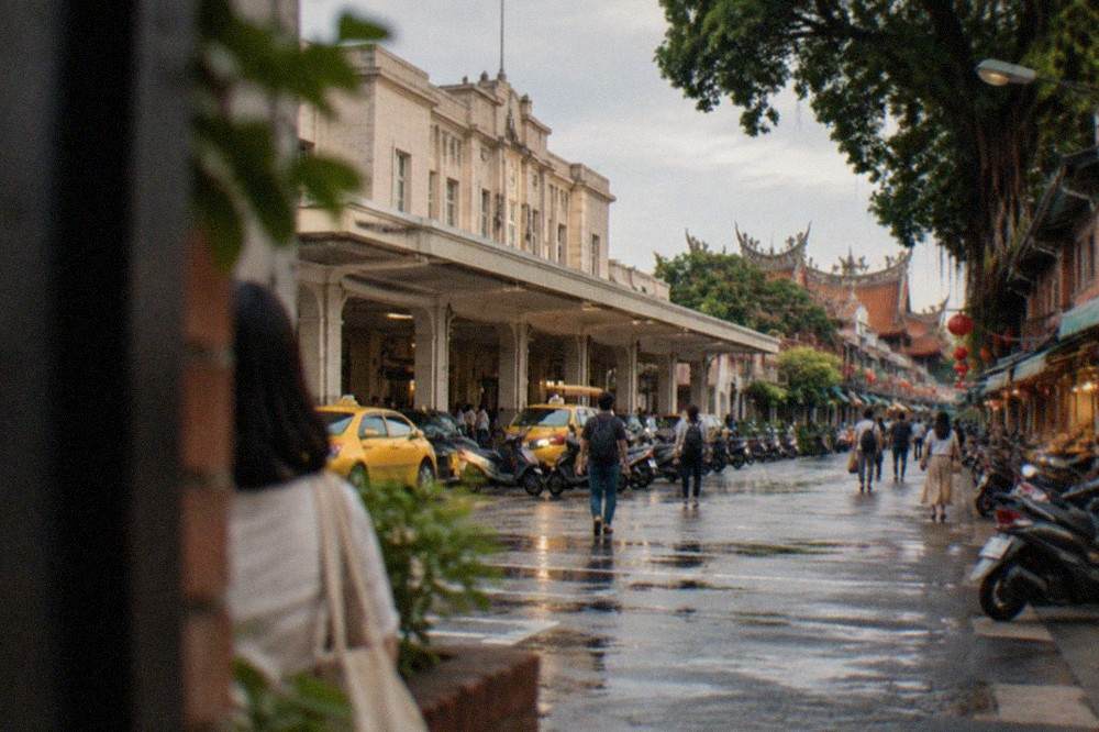 An old Taiwanese street lined with low brick buildings, lanterns and people browsing in the late afternoon