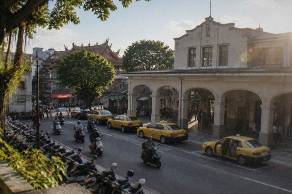 Historic Tainan architecture with red brick walls and tropical trees under a blue sky