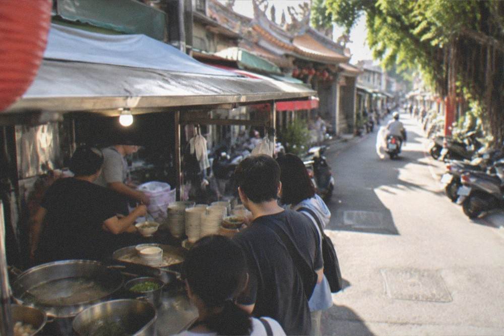 A lit food stall serving bowls of soup to customers at a Tainan night market