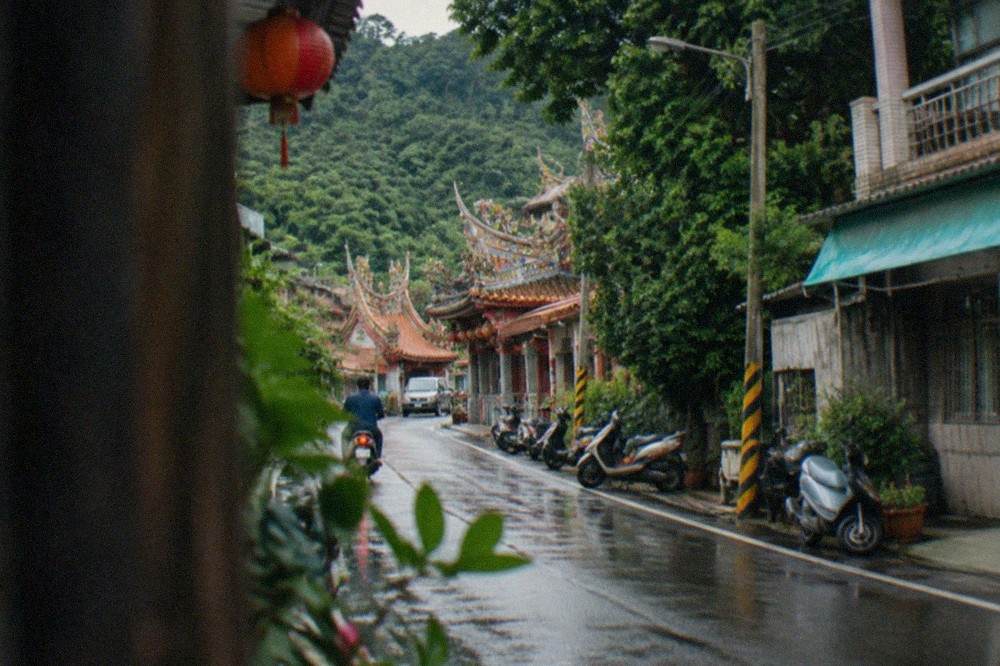 A narrow mountain road with green slopes rising on both sides