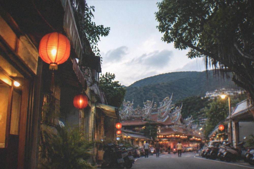 A small resort town at dusk with lights among dark hills