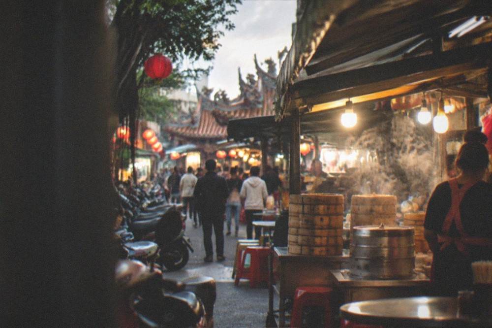 Illuminated food stalls and a crowd in a Tainan street after dark