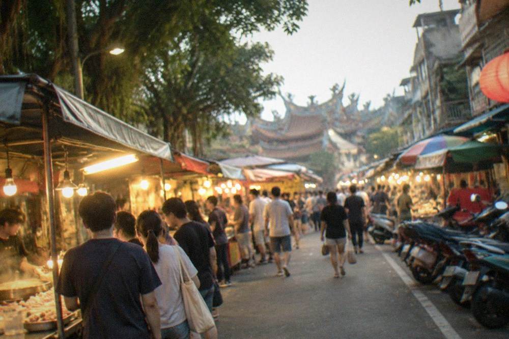 Rows of food stalls with hanging lights and queues of customers at a Tainan night market after dark