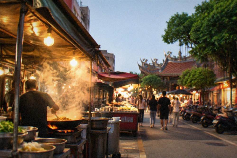 Steam rising from food stall woks under warm lights at a Tainan night market on a dry evening