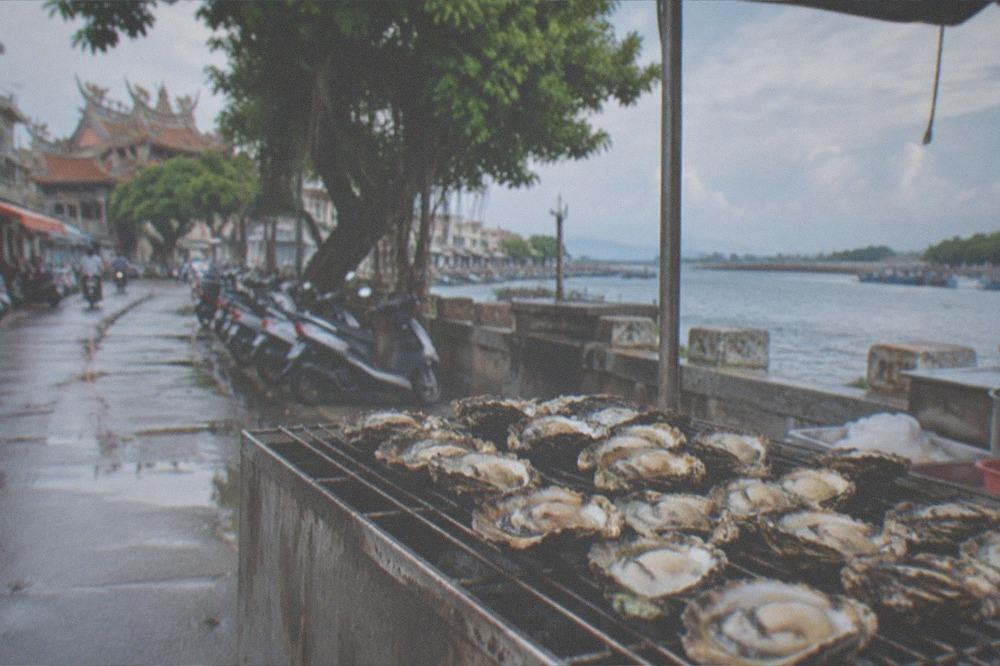 Grilled oysters served on a rack at a seafood stall beside the lagoon