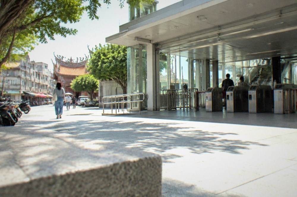 A clean modern station concourse with ticket gates, signs and a few travelers with luggage