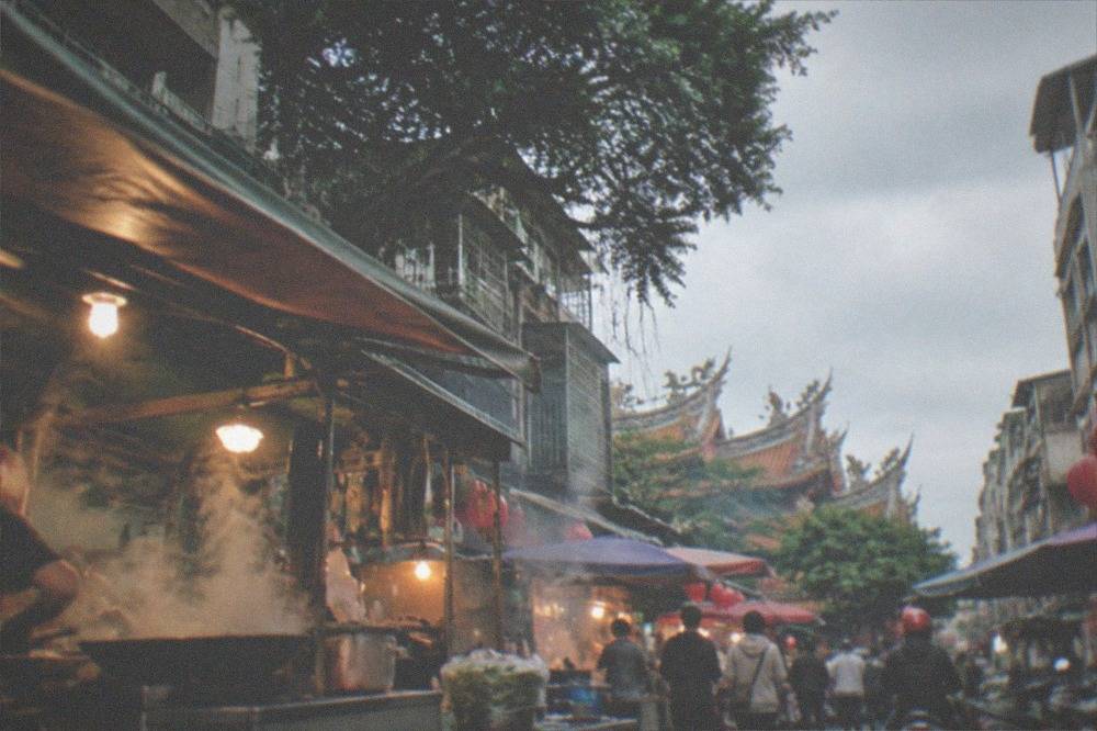 Crowded food stalls with steaming woks along a Tainan night market lane