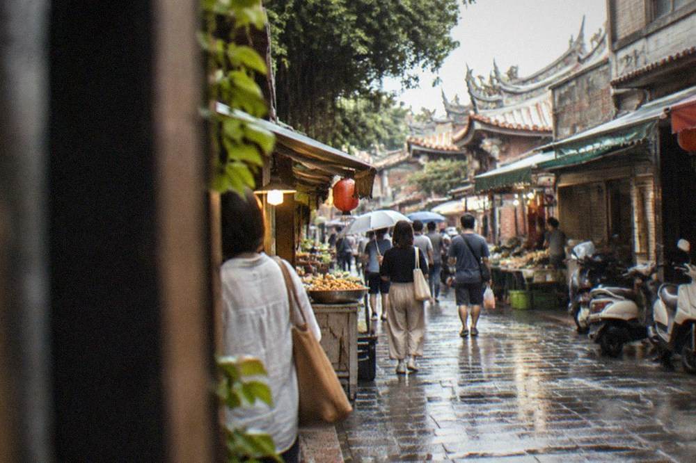 Shoppers walking past open-fronted food stalls on a historic street in Xinhua