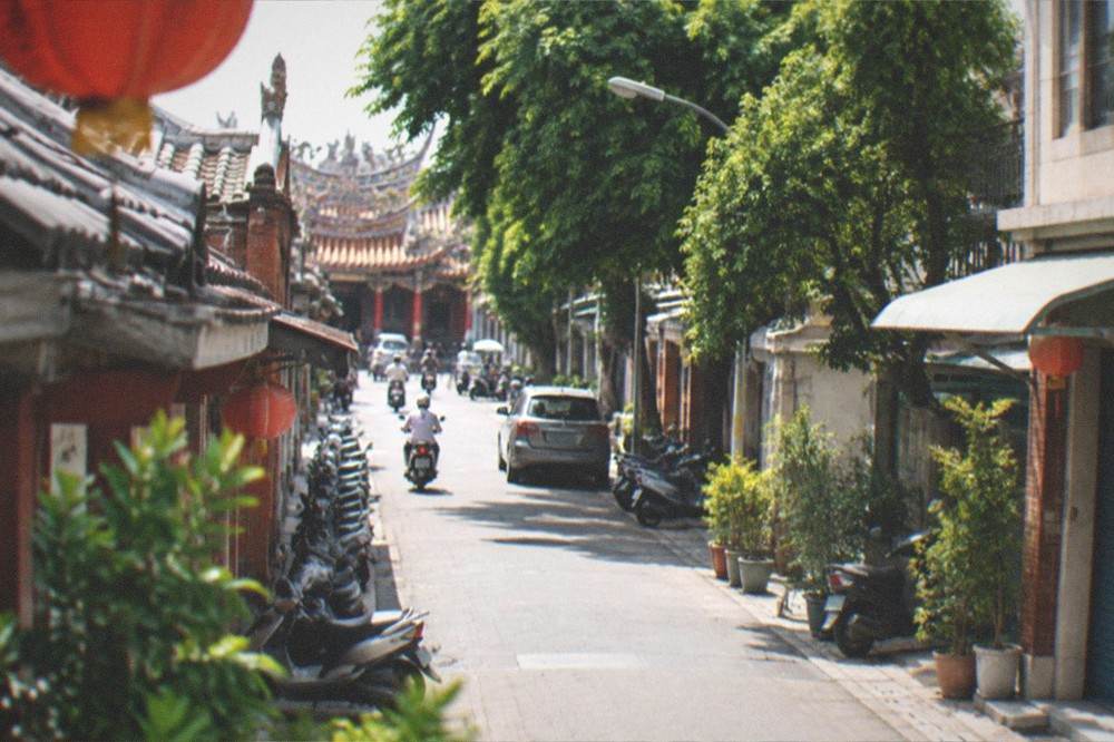 A visitor in a qipao dress standing in front of a decorated historic storefront