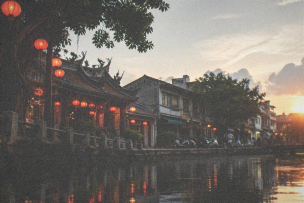 Glowing lantern installations reflected in still harbor water at night