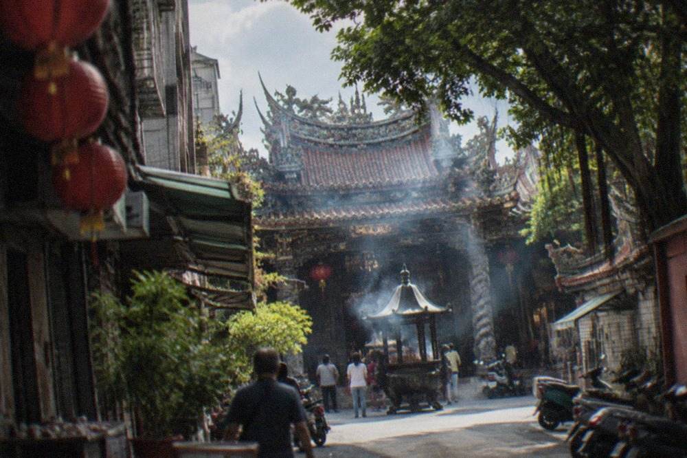 A historic temple courtyard in Tainan with incense smoke rising in front of ornate carved halls