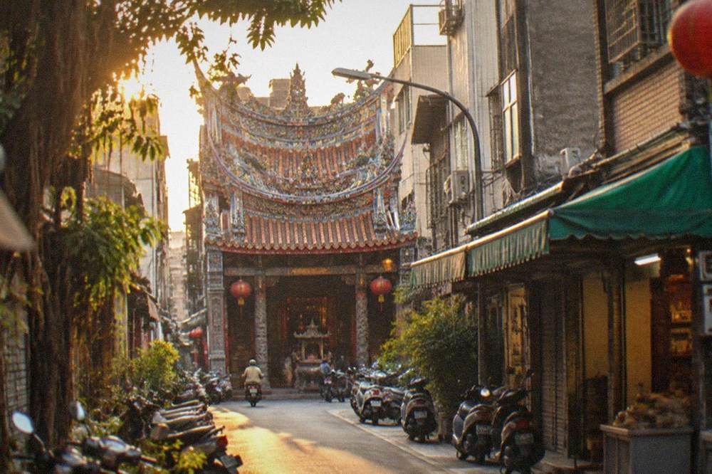 A Tainan street with scooters parked along an old shopfront in the old city