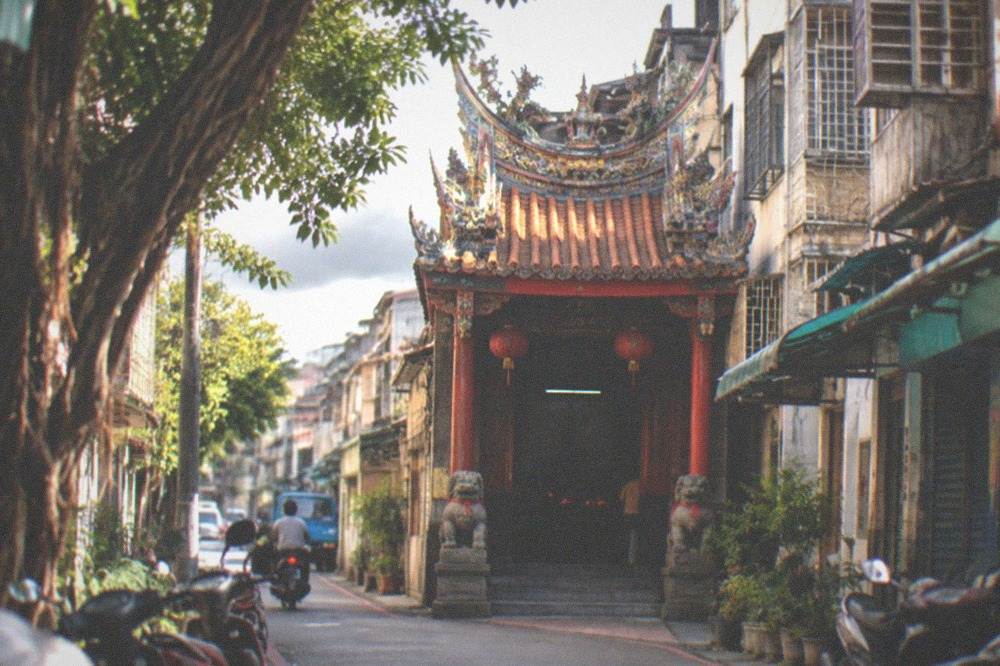 A red temple gate with stone lions in a Tainan lane