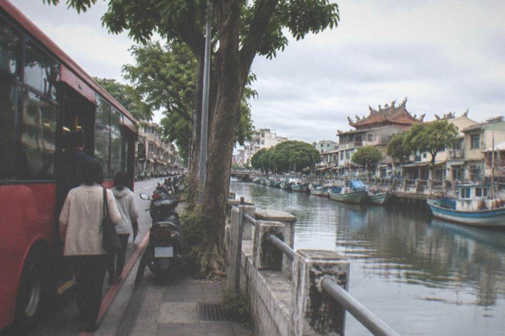A red city bus at a stop on a Tainan street, with passengers boarding