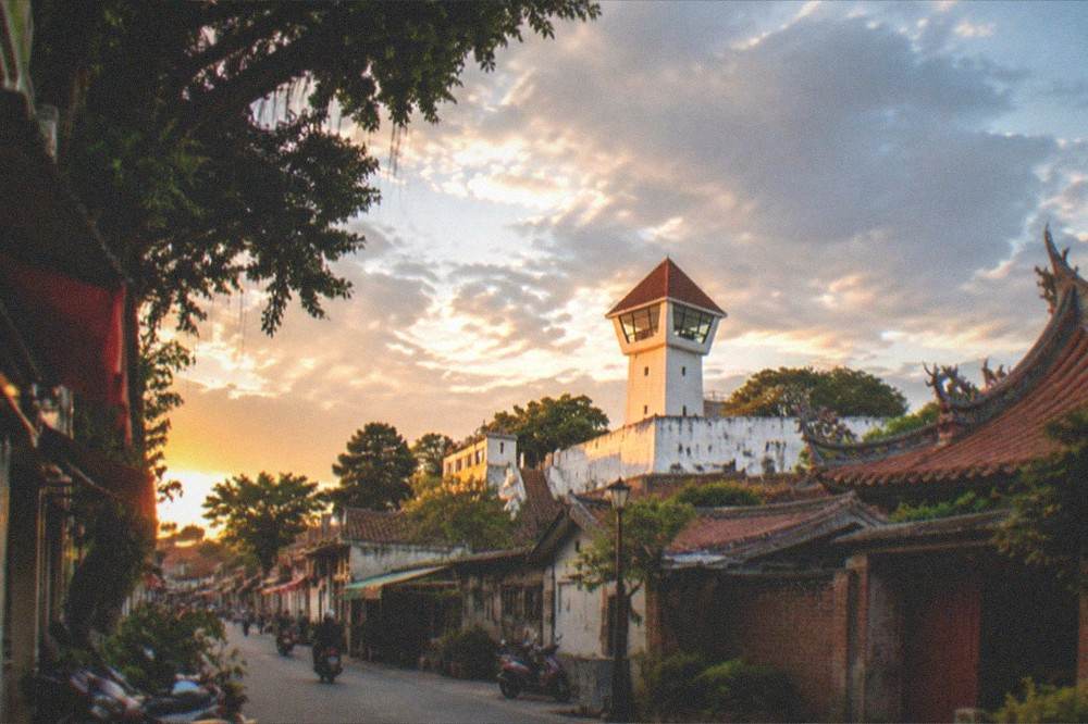 Sunset light on white fort walls and a red-tiled tower above the old Anping rooftops