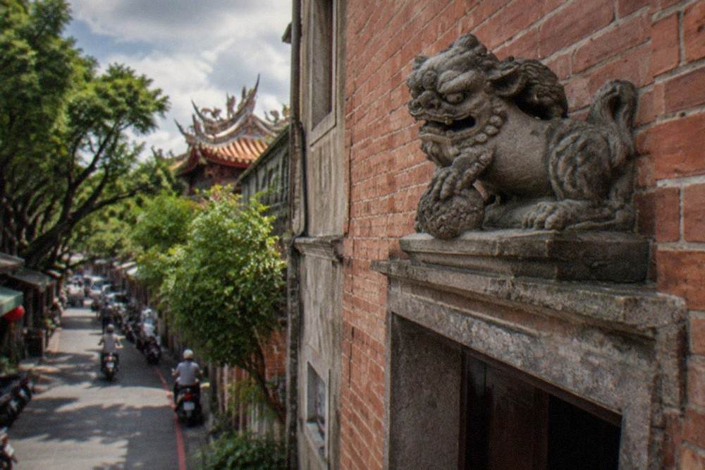 Brick wall detail with a carved sword lion mounted above an old doorway