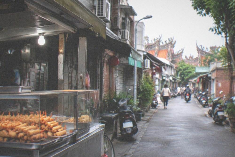 A food stall counter stacked with fried shrimp rolls ready to serve
