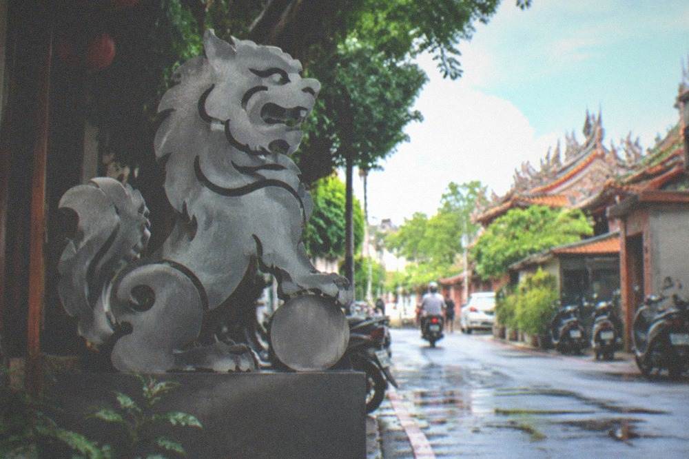 A sword lion emblem on a modern street installation in Anping beside an old lane