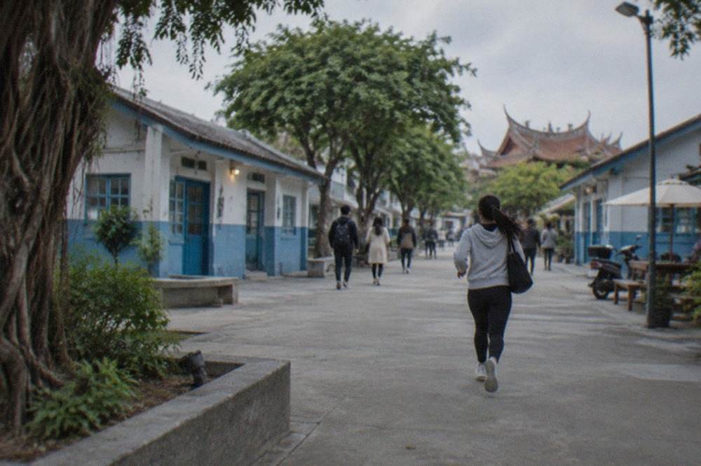 A wide plaza in a Tainan culture park with old low buildings, murals and visitors walking between them