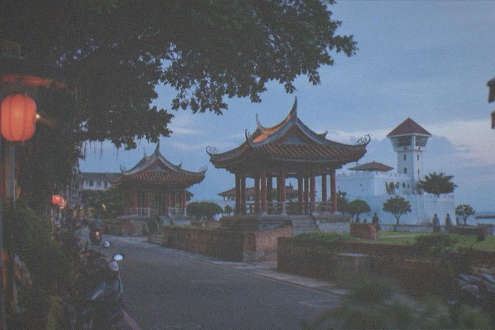 A white-walled fort with a lookout tower standing on open ground near the coast