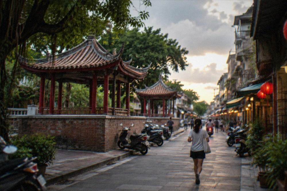 A narrow old street at dusk with lanterns and small shopfronts along both sides