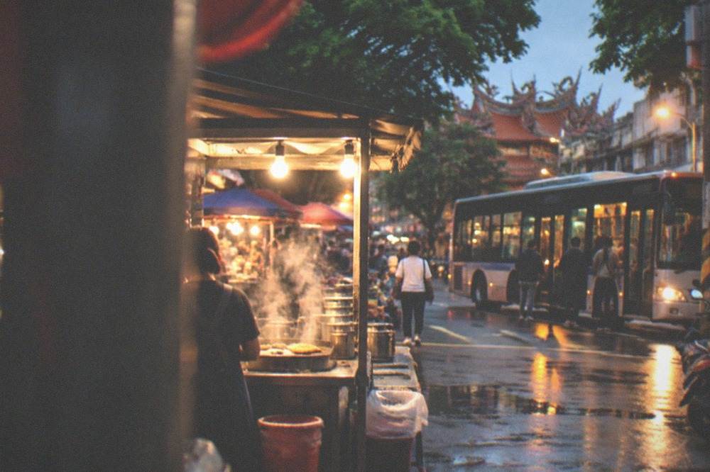 A city bus stopping at a lit street at night with passengers boarding