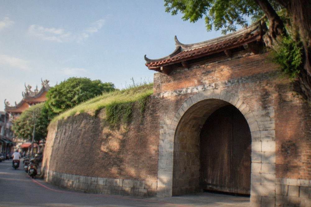 Close view of a stone gate arch with weathered walls and a wooden door