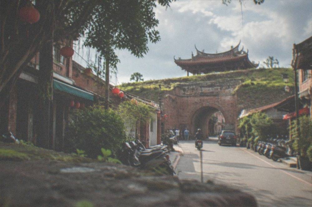 A narrow old street lined with low brick buildings and hanging lanterns