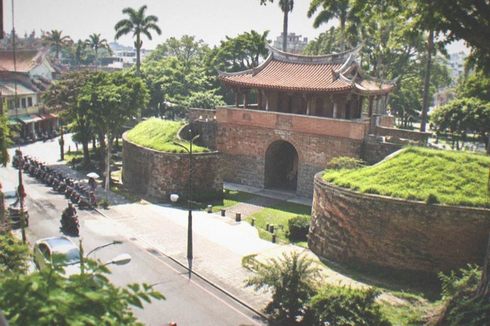 Palm trees and a historic stone gate in a green park under bright sun