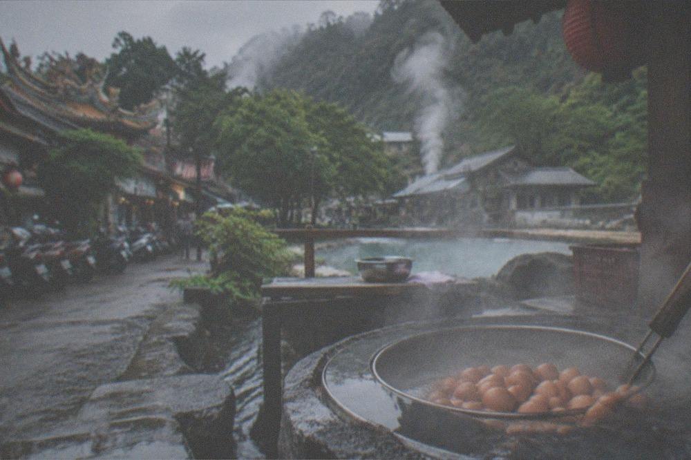 A tray of hot spring eggs steaming beside a pool at an outdoor stall