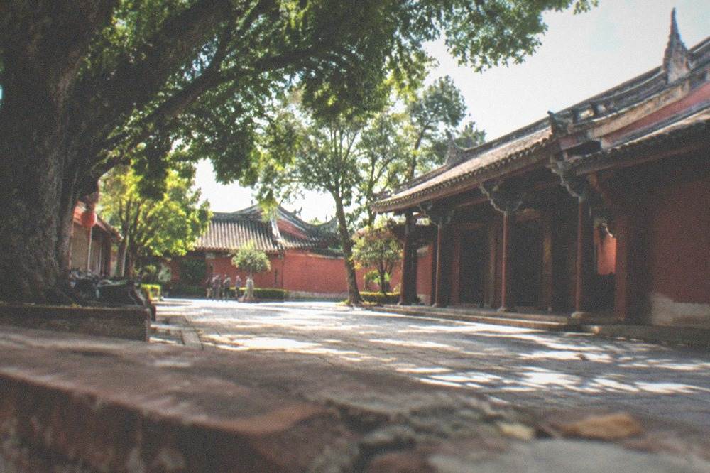 The courtyard and red walls of the Tainan Confucius Temple under trees