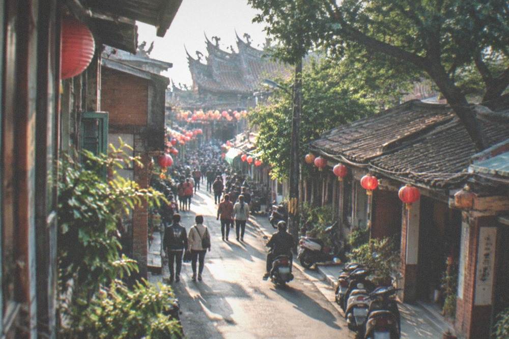 An old street glowing under lanterns during an evening festival crowd