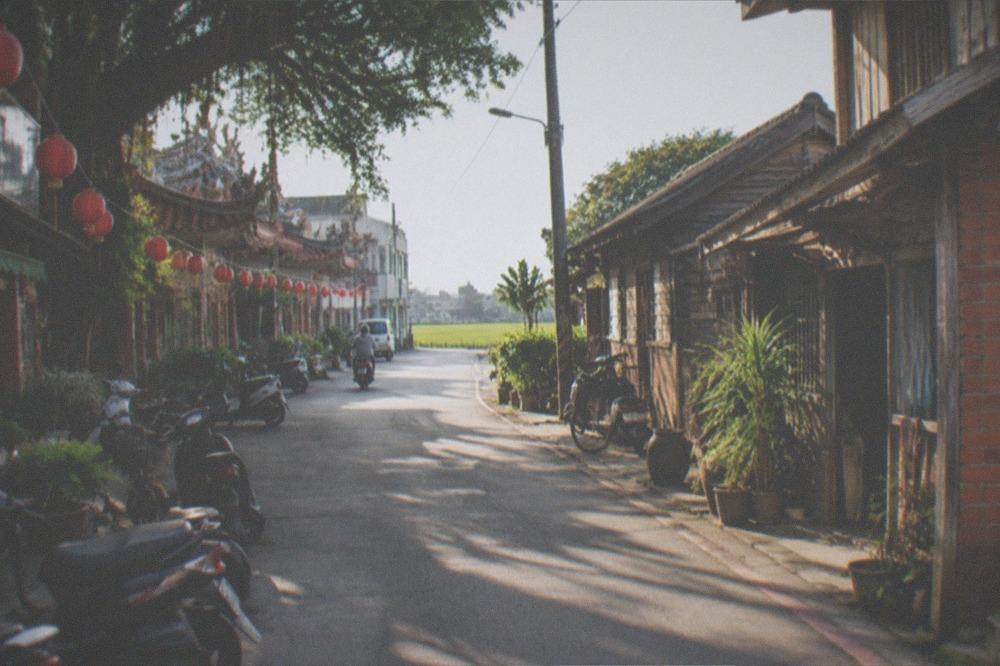 Two old streets side by side, one rural with fields beyond and one urban with lanterns