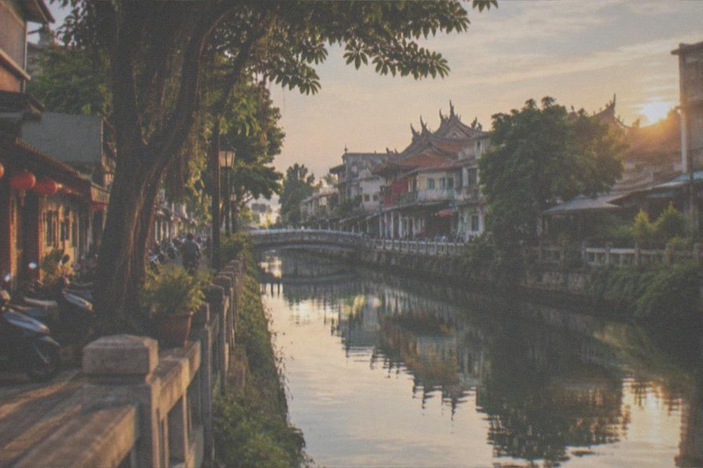 A canal in Anping at golden hour with old buildings reflected in the water
