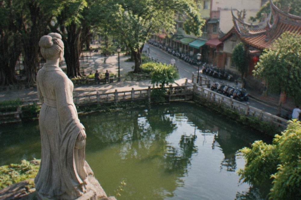Statue of a young woman in traditional dress overlooking the water at a Tainan park