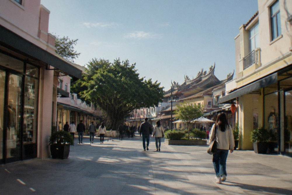 Shoppers walking past international brand storefronts inside a bright mall corridor