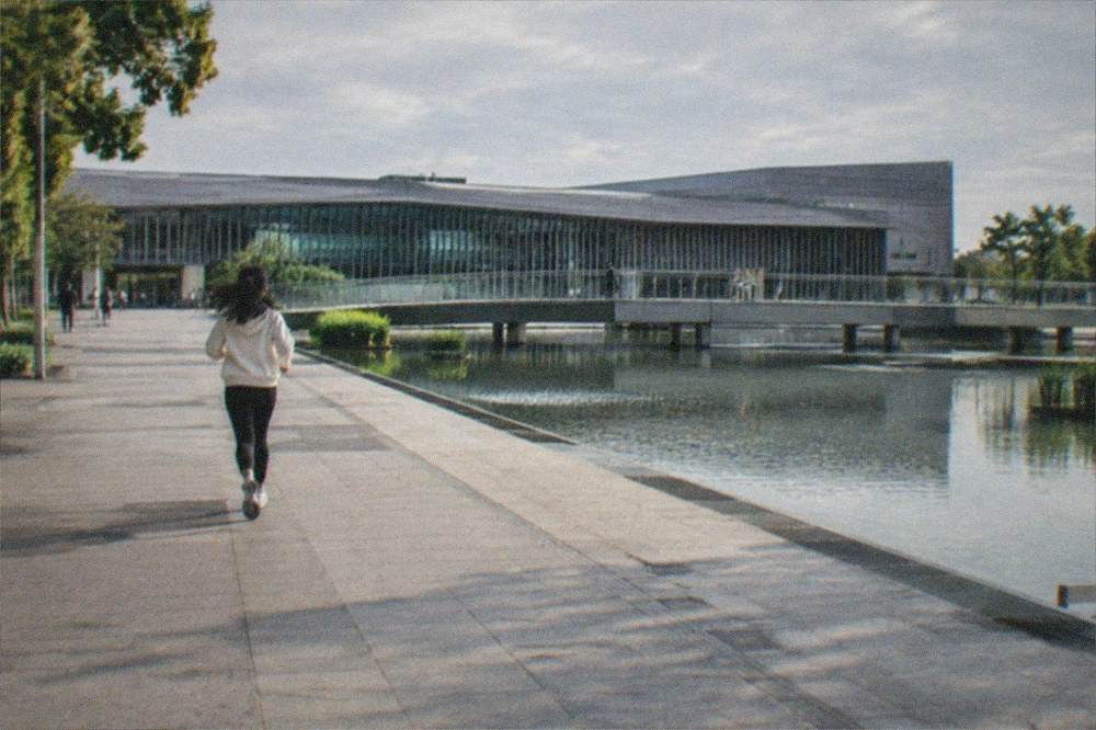 A wide museum plaza with a still water feature and an overcast sky