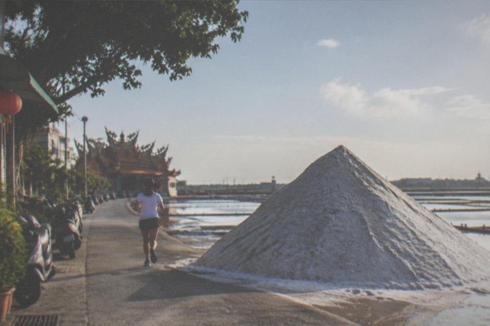 Bright sunlight on a white salt slope with heat haze over the flat coastal plain