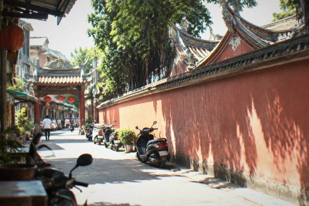 A narrow old street in Tainan with traditional shopfronts and a temple gateway
