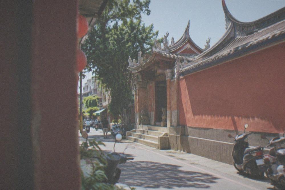 Sunlit temple gateway with stone steps and clear sky in Tainan