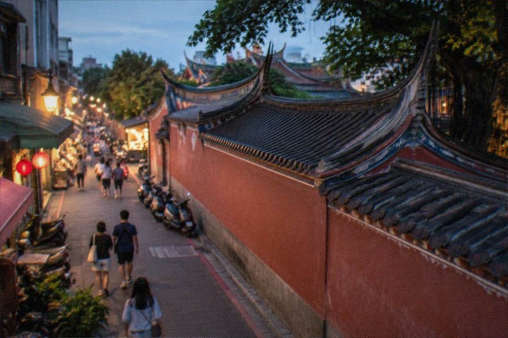 Evening street scene in Tainan with lit shopfronts and visitors walking